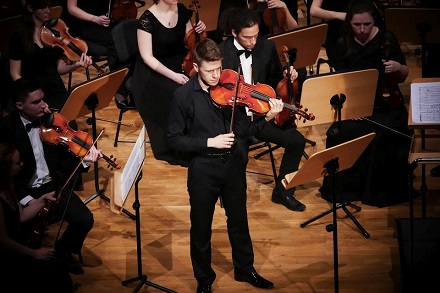 Polish violist Jan Snakowski performing as soloist on stage with a youth orchestra